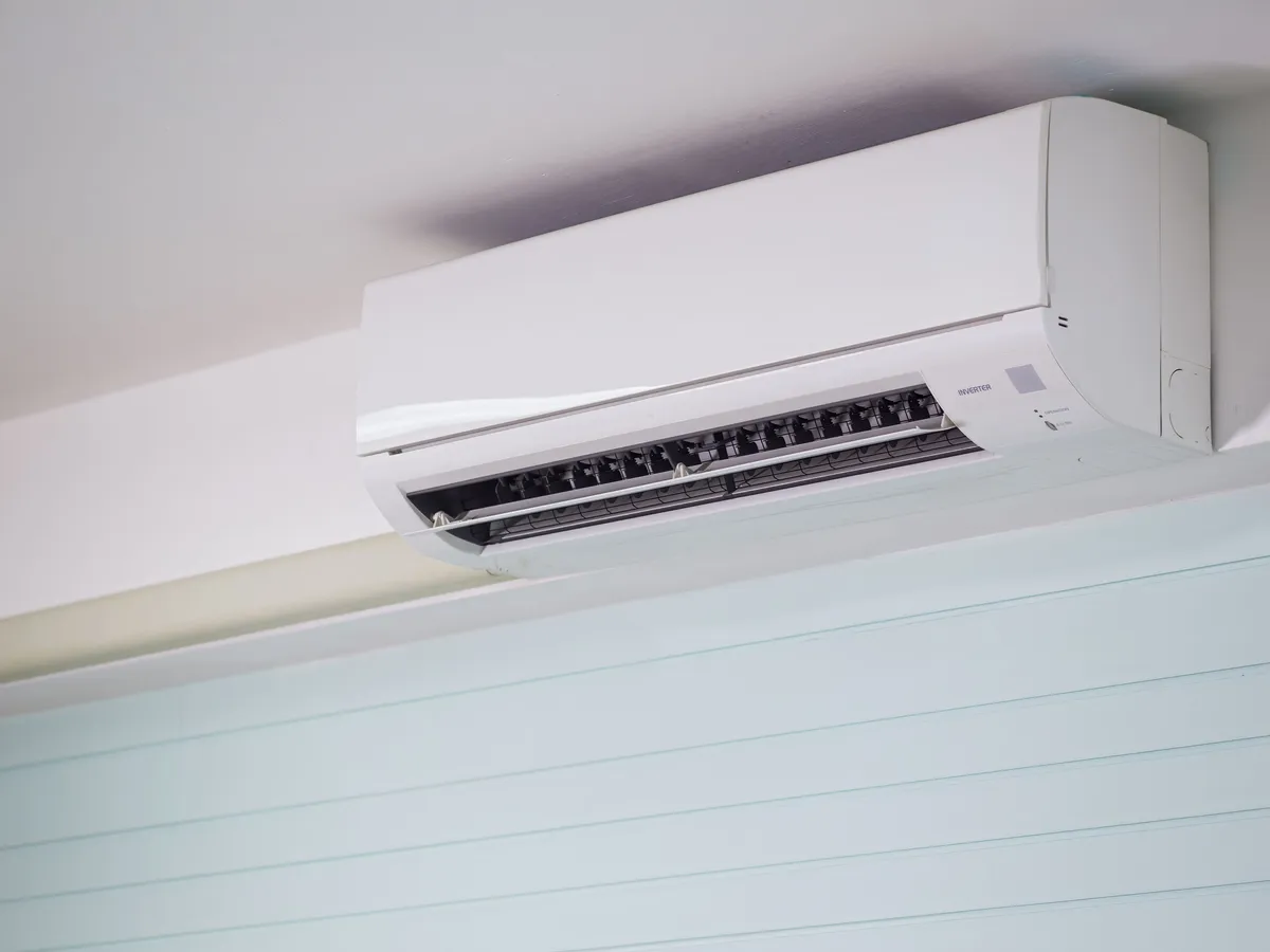 White wall-mounted inverter mini-split air conditioner indoor unit mounted high on a wall