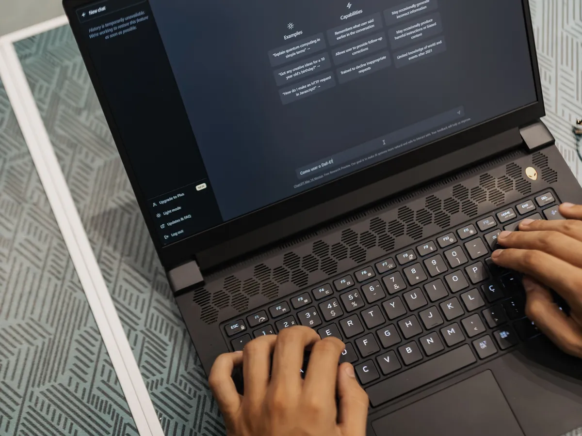 Man typing on a laptop displaying an AI chat assistant at a desk