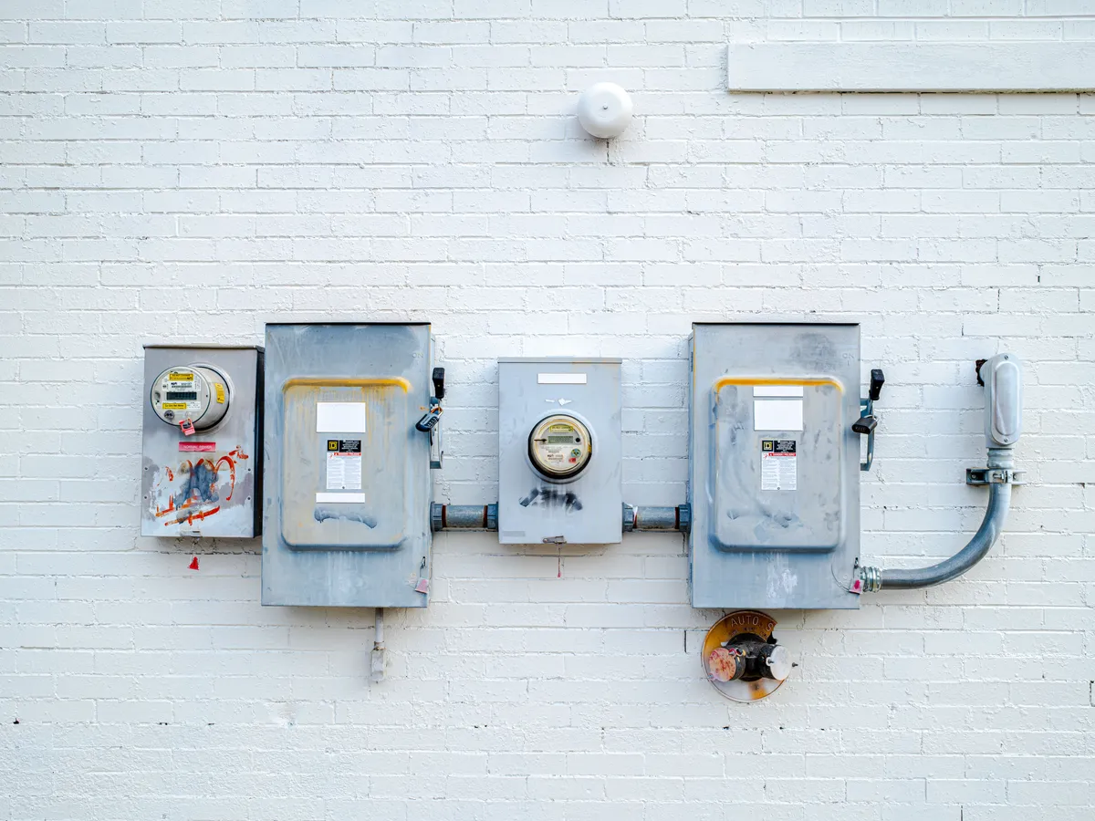 Electrical disconnect boxes and two meters mounted on a white painted brick wall