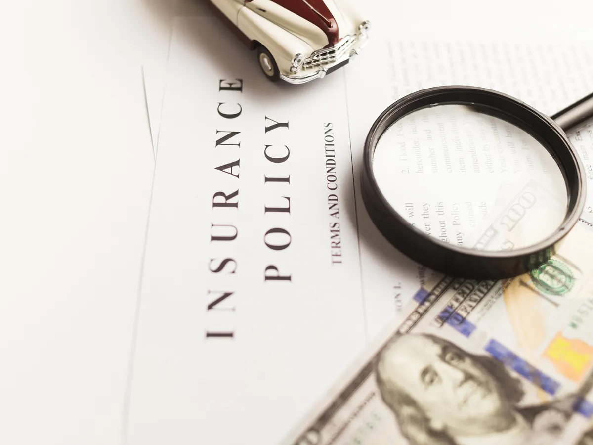 Magnifying glass resting on an insurance policy document