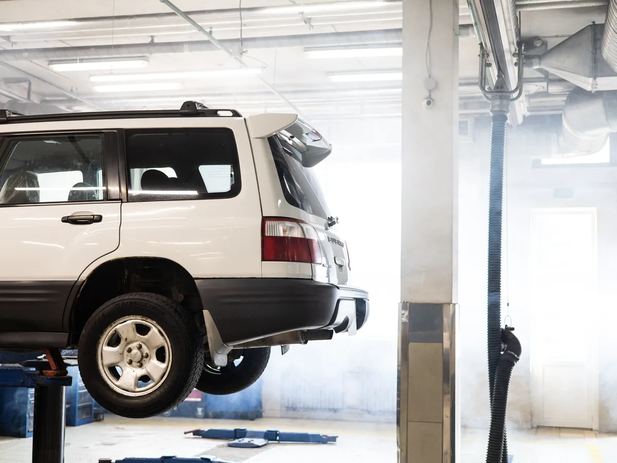 White SUV raised on a lift inside an auto repair shop
