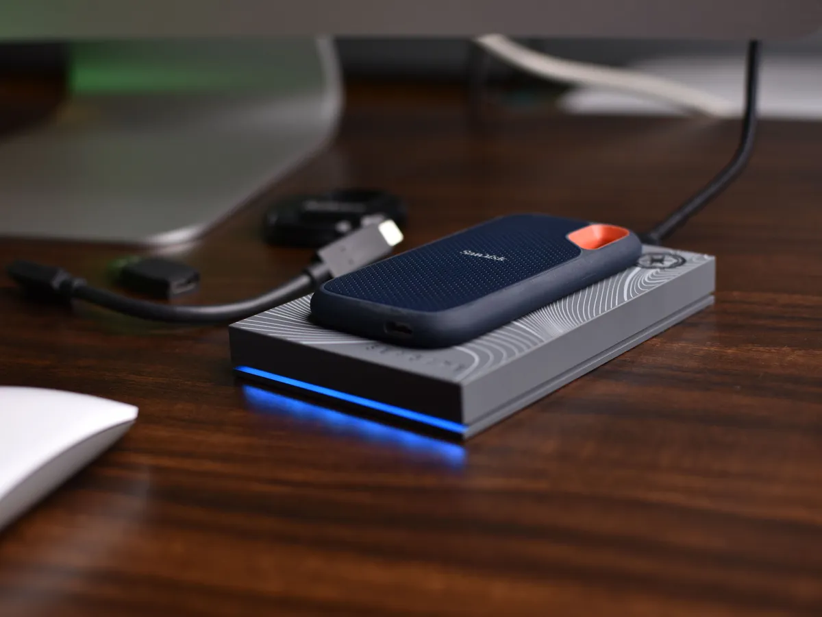 SanDisk portable SSD resting on a small external drive on a wooden desk