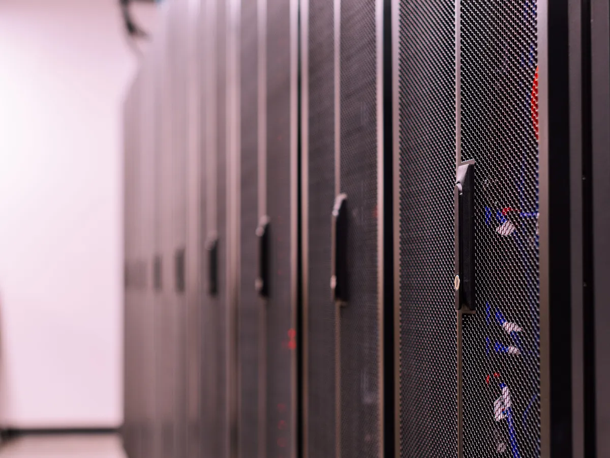 Rows of black mesh-door server racks in a data center aisle