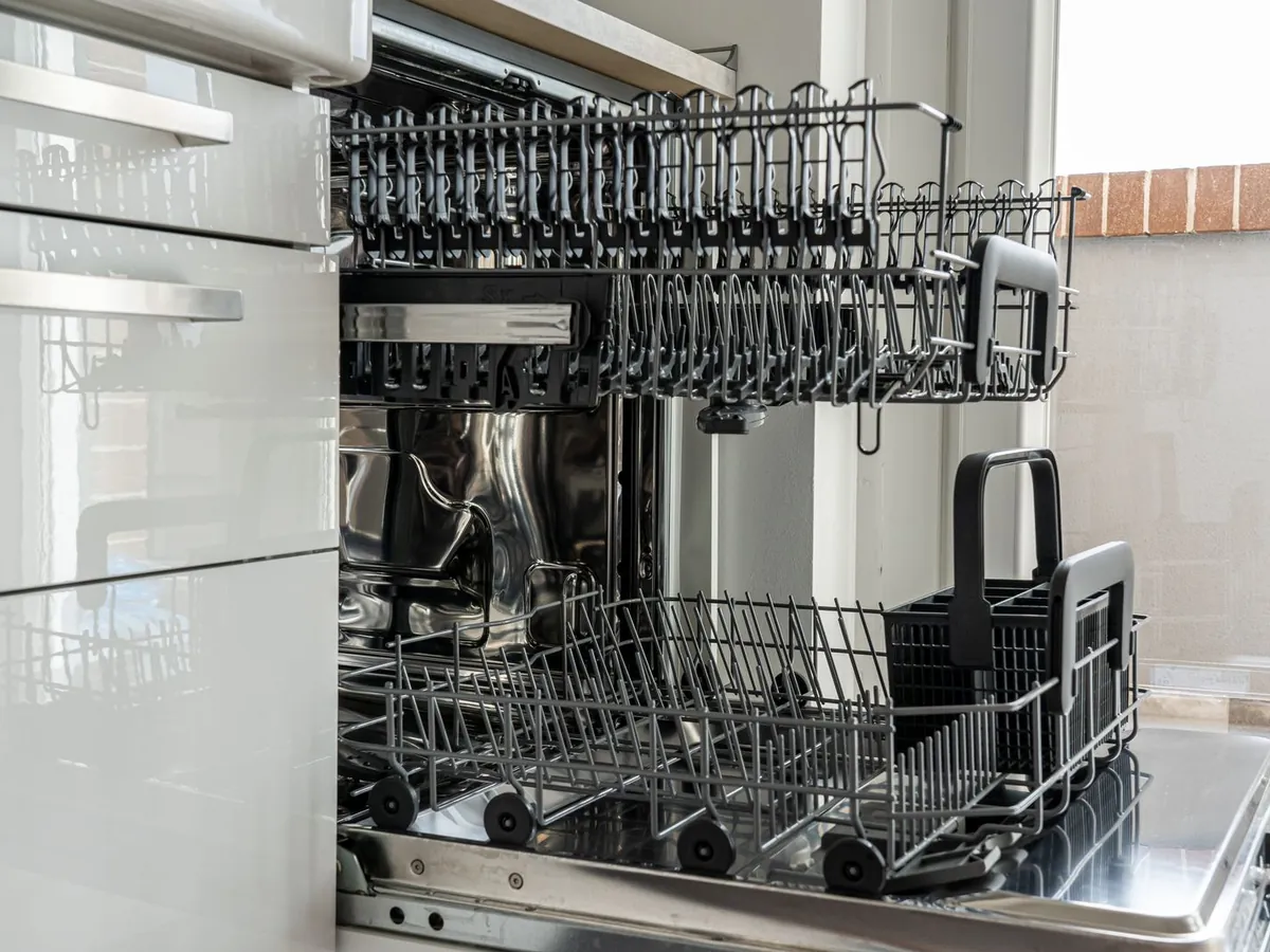 Open dishwasher with upper and lower racks pulled out in a kitchen