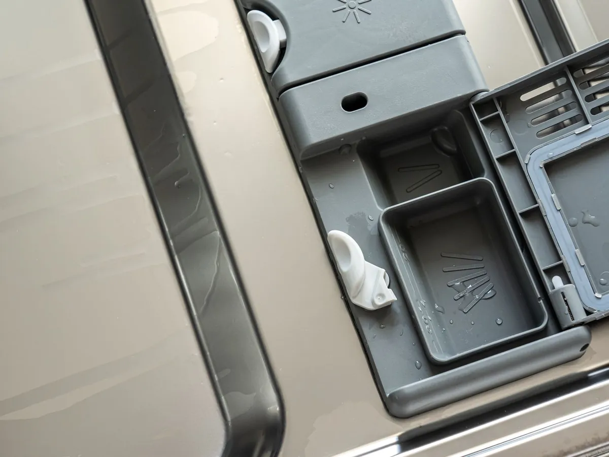 Close-up of a dishwasher detergent dispenser and rinse aid compartment