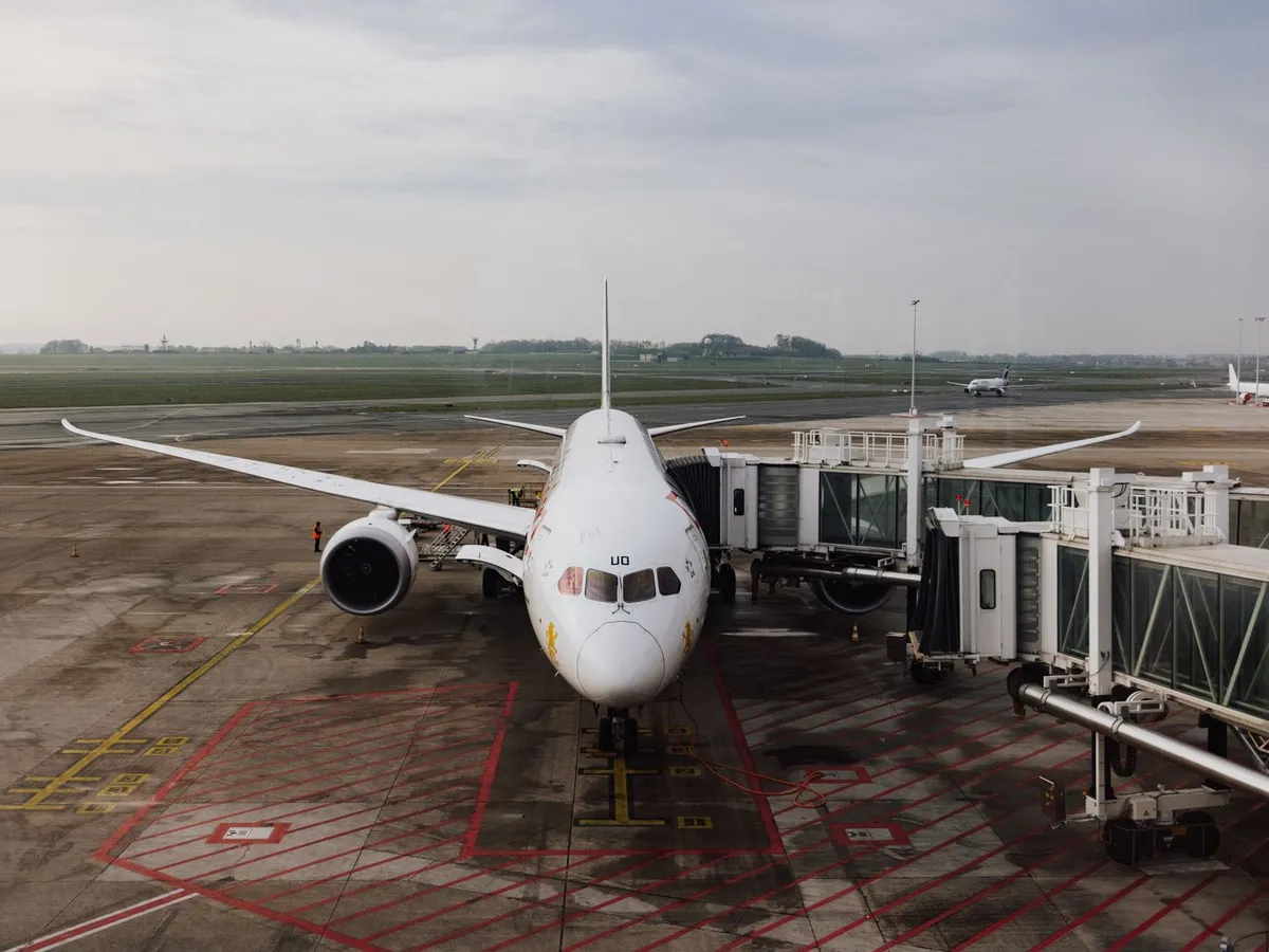 Jet airplane docked at an airport terminal gate under cloudy skies
