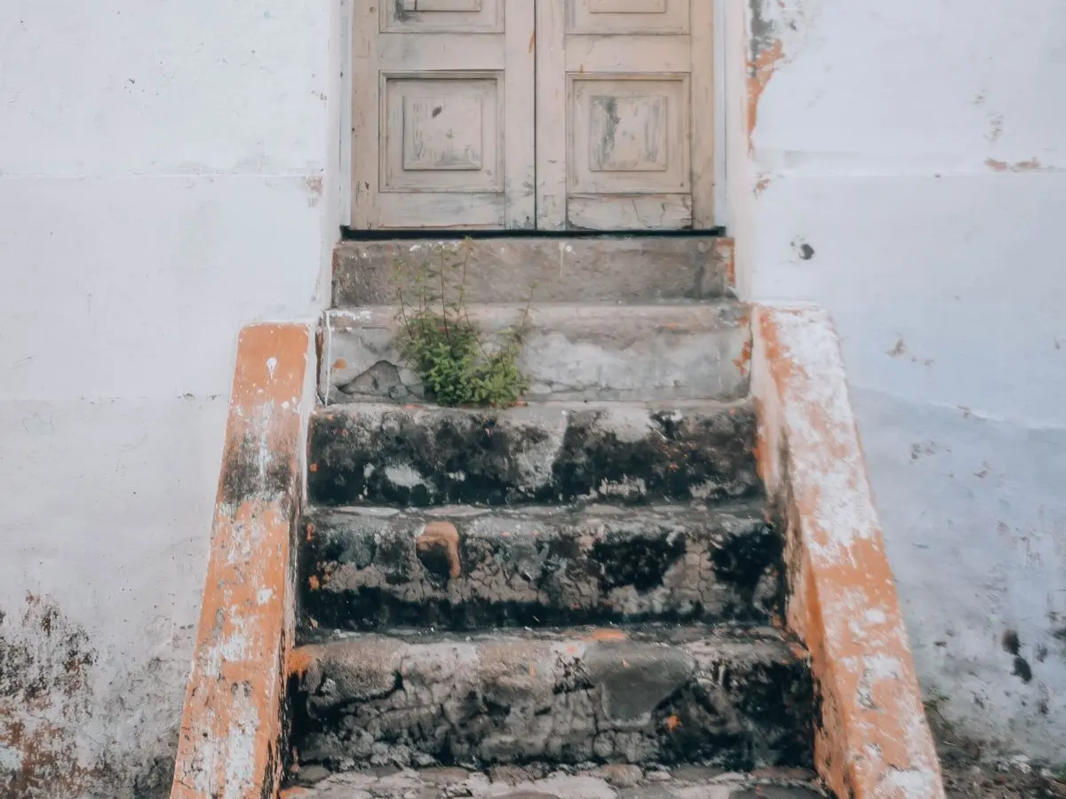 Old wooden entry door at the top of worn concrete steps