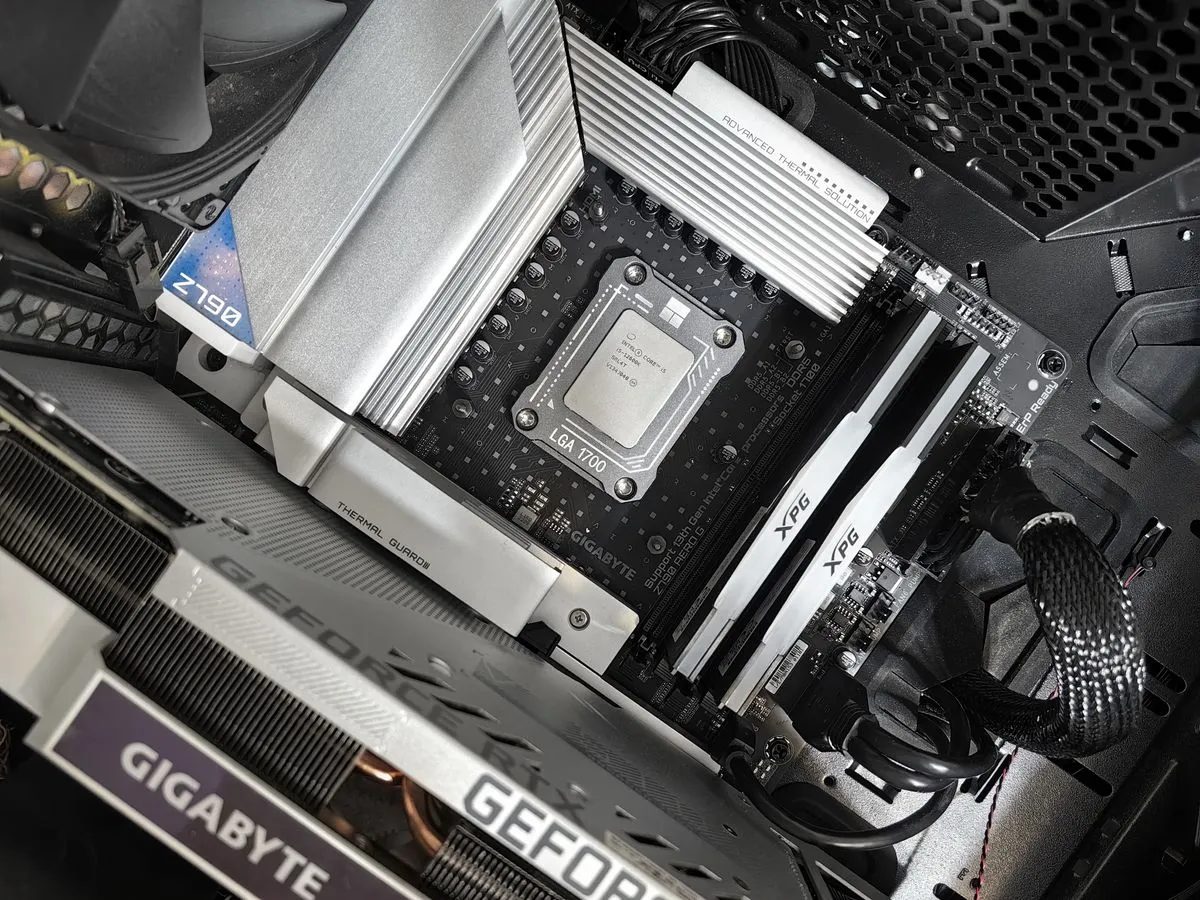 Top-down view of a PC motherboard with a CPU socket, white RAM sticks and a graphics card installed in a black case