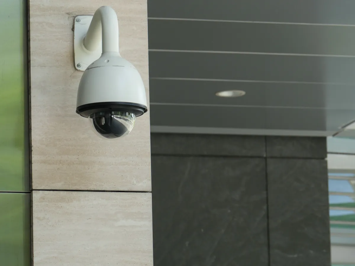 White dome security camera mounted on a stone wall outside a building