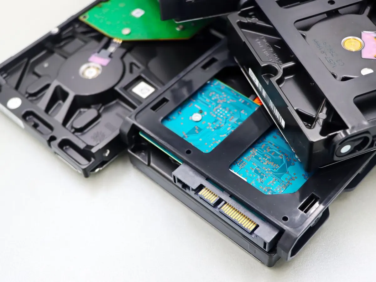 Stack of internal 3.5-inch hard drives showing circuit boards and SATA connectors on a light gray surface