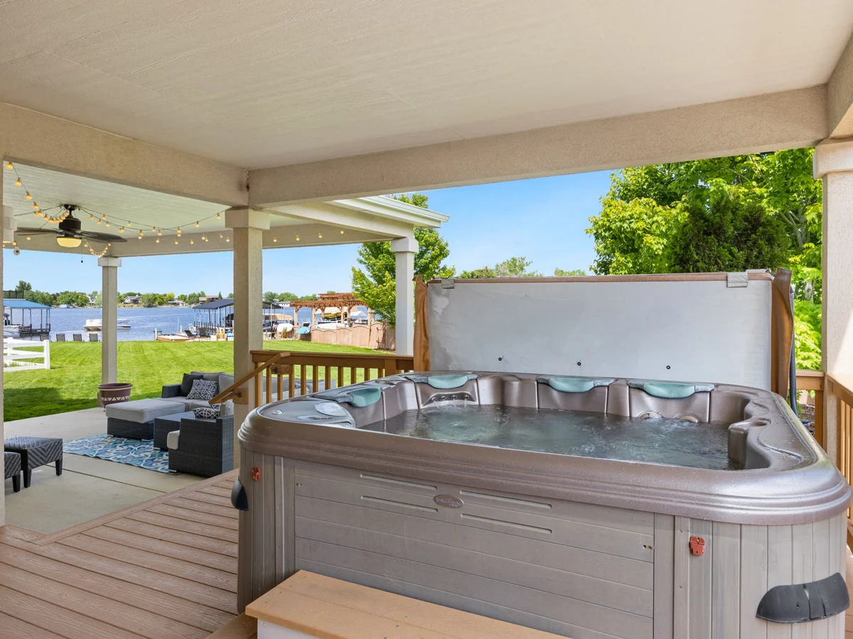 Covered hot tub on a wooden deck beside a lake