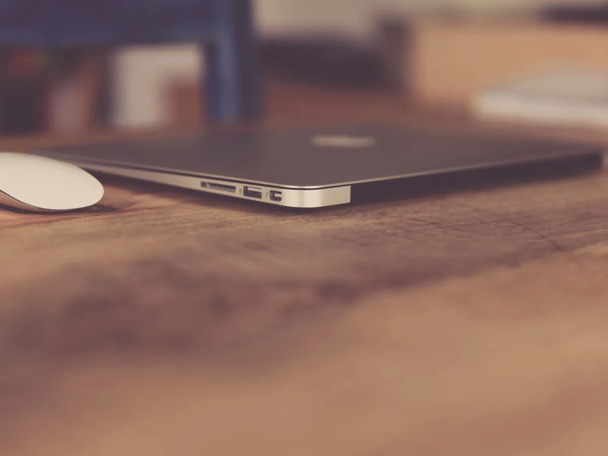 Laptop and mouse on a wooden desk in a modern workspace