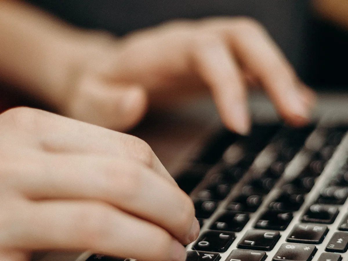 Person typing on a laptop keyboard at a desk