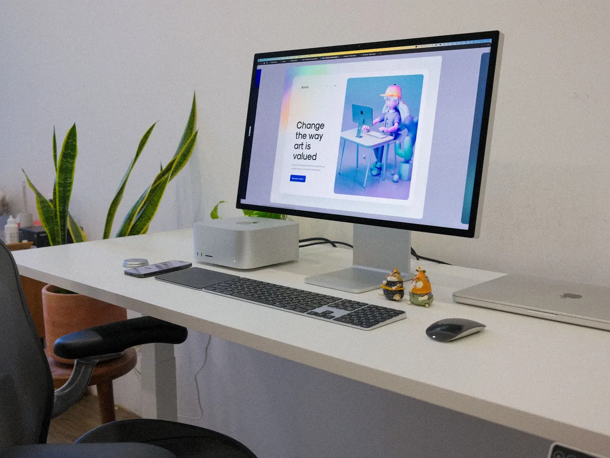Mac Studio, Apple display, keyboard and a closed MacBook on a white desk