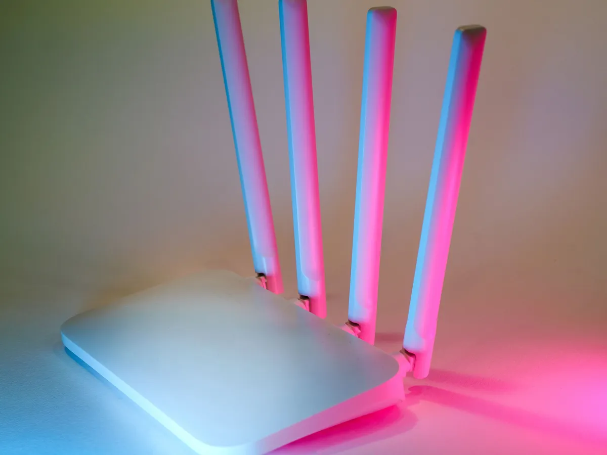 White four-antenna Wi-Fi router lit with pink and blue light