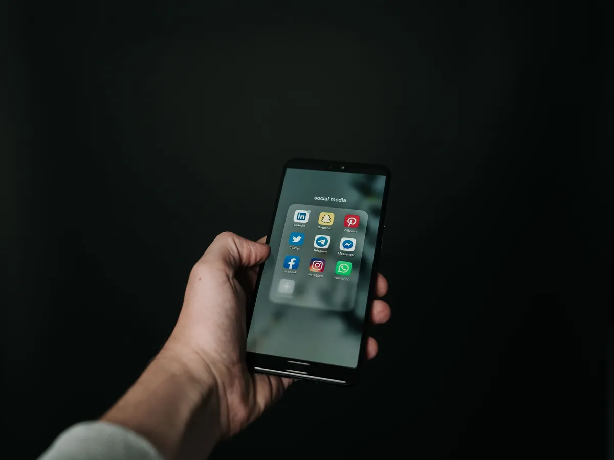 Hand holding a black smartphone against a dark background