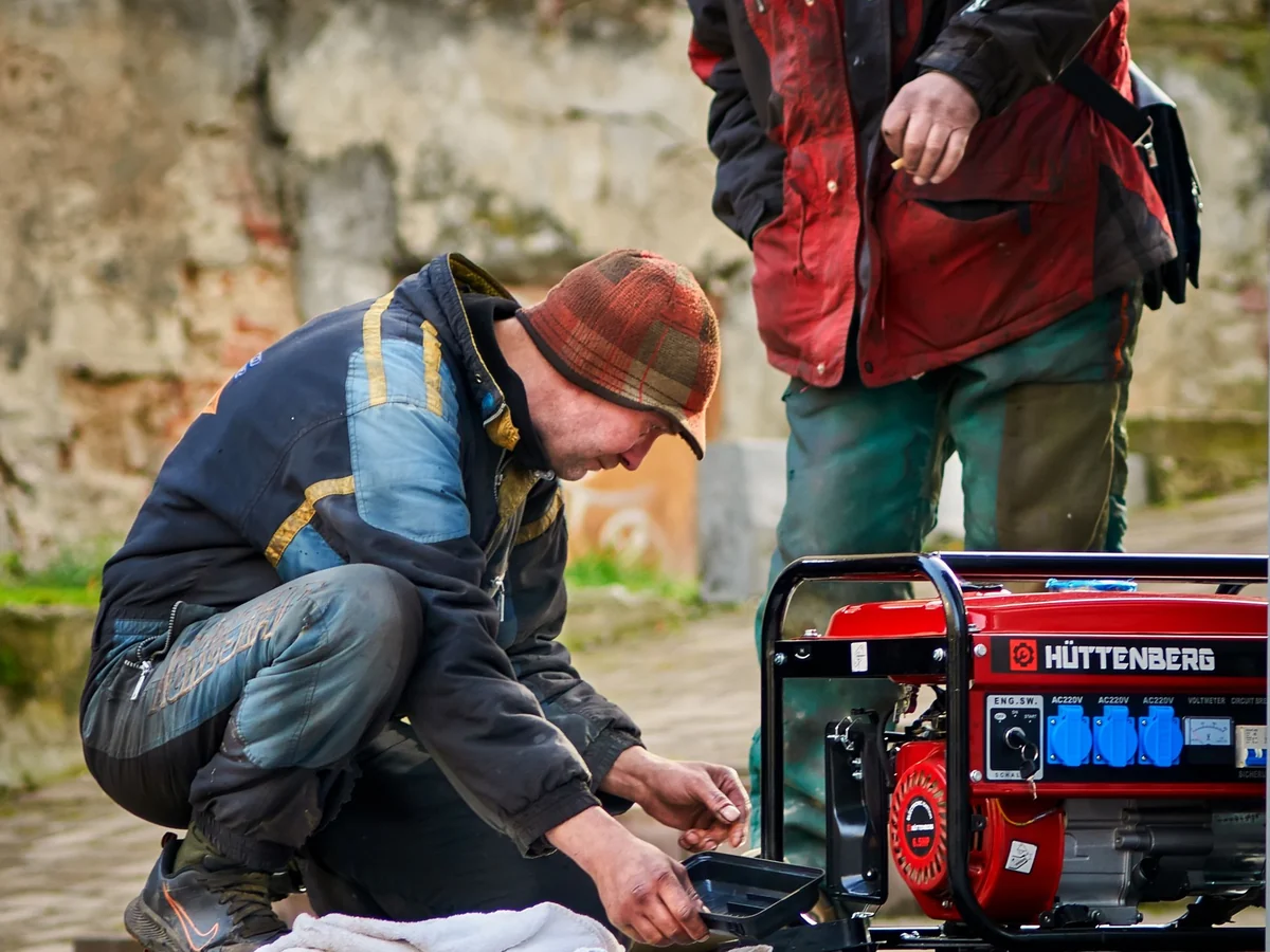 Two technicians working on a portable generator outdoors