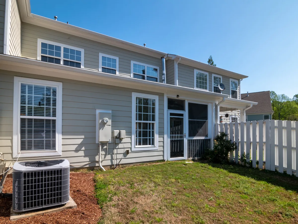 Back of a two-story house with gray lap siding, white-trimmed windows, a screened porch, and an outdoor air conditioner