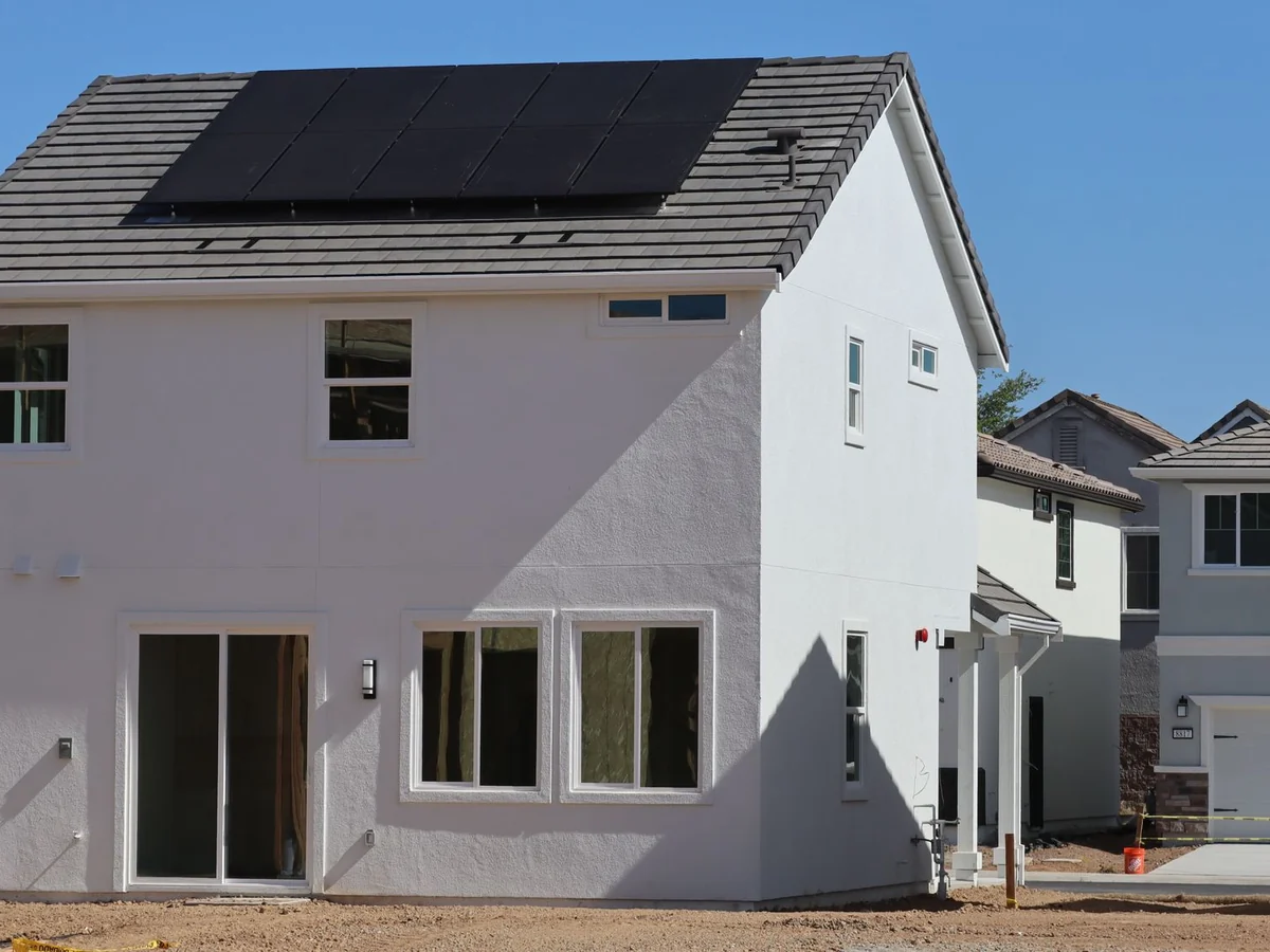 Rooftop solar panels on a white house under a clear blue sky