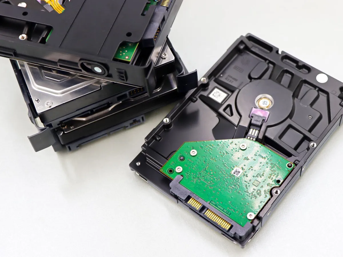 Stack of bare 3.5-inch internal hard disk drives with silver metal casings on a light surface