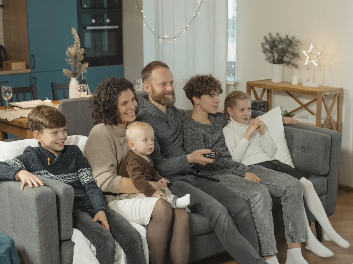Family sitting together on a sofa watching television in a living room