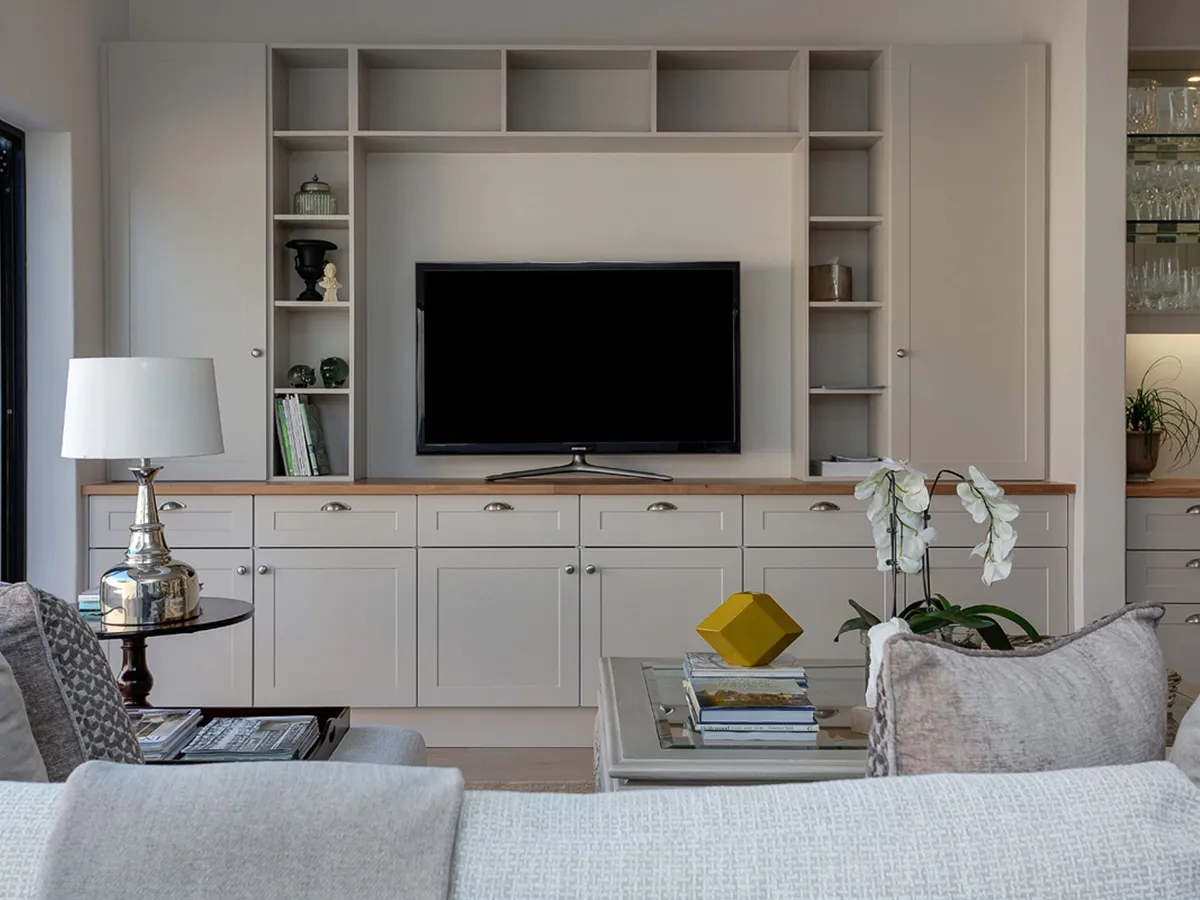 Flat-screen TV in a living room recessed into built-in shelving beside a sofa