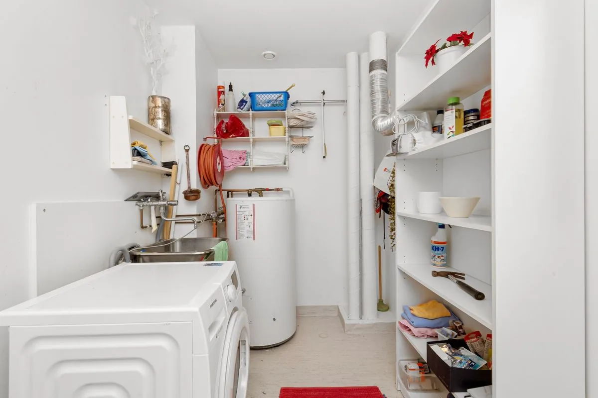 Laundry room with a cylindrical water heater beside a washing machine