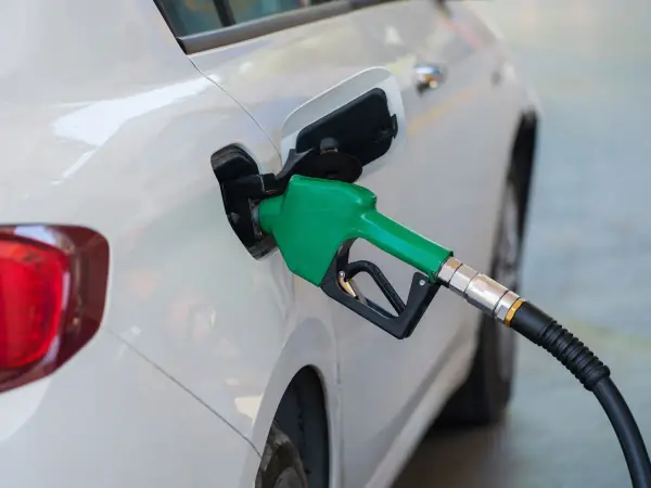 Green fuel nozzle refueling a white car at a gas station