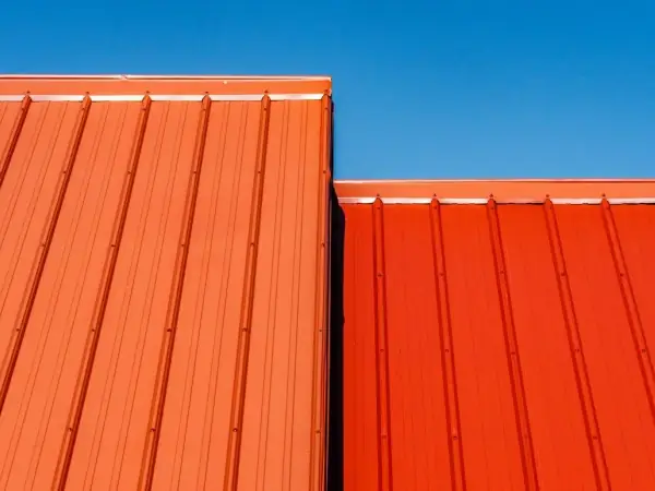Orange standing-seam metal roof panels against a blue sky