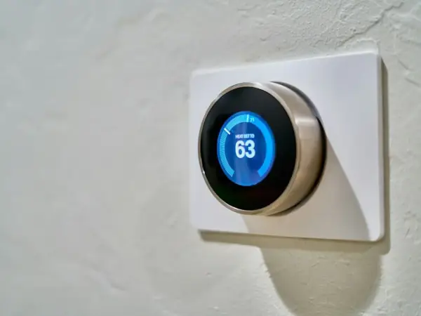 Smart thermostat on a wall showing 63 degrees